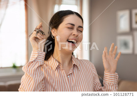 Purchase of real estate. Portrait of happy young caucasian woman realtor shows keychain and keyring. Concept of leasing, business and mortgage 101128771