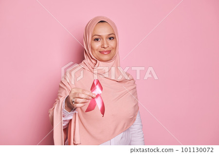 Details on pink satin awareness ribbon in Muslim Woman's hands - emblem of fighting breast cancer and supporting patients and survivors, isolated on pink background. October awareness month campaign Details on pink satin awareness ribbon in Muslim Woman's hands - emblem of fighting breast cancer and supporting patients and survivors, isolated on pink background. October awareness month campaign 101130072