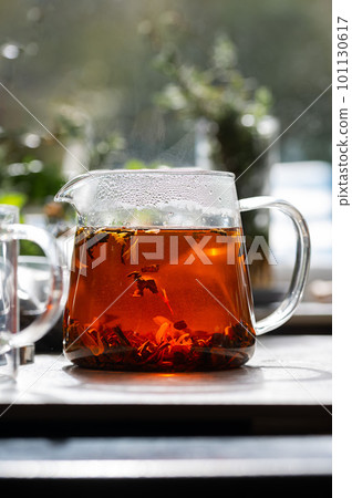 Glass teapot of loose black leaf tea with dried flowers. Drinking tea concept. Soft focus 101130617