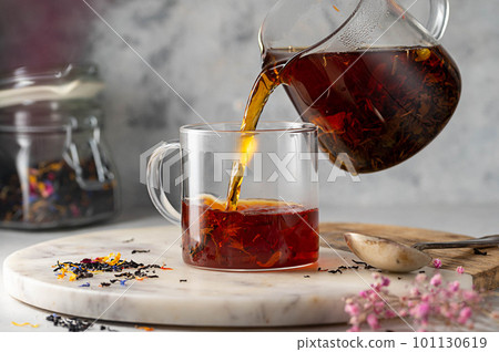 Pouring freshly brewed black loose leaf tea in glass cup. Lifestyle drinking tea. 101130619