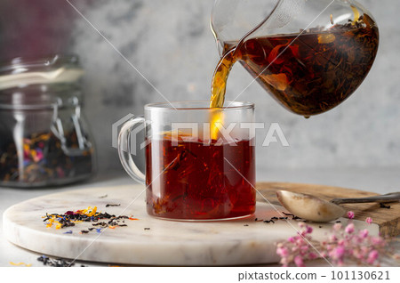 Pouring freshly brewed black loose leaf tea in glass cup. Lifestyle drinking tea. 101130621