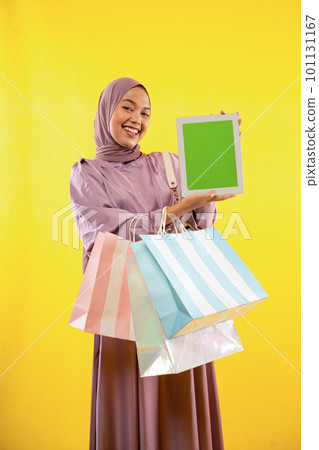 muslim woman in hijab with shopping bag showing pad screen muslim woman in hijab with shopping bag showing pad screen 101131167