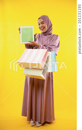 hijab girl with shopping bag showing pad screen with yellow 101131193