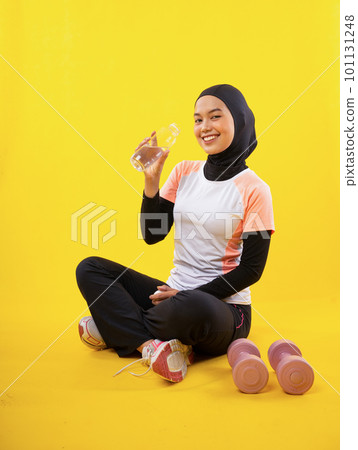 smiling Asian Muslim woman in sportswear drinking water with bottle smiling Asian Muslim woman in sportswear drinking water with bottle 101131248