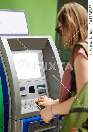 Vertical shot of young fashionable girl stands back near cash machine, withdraws money, types on buttons after inserting credit card, enters pin code, uses ATM machine. Finances and money concept. Vertical shot of young fashionable girl stands back near cash machine, withdraws money, types on buttons after inserting credit card, enters pin code, uses ATM machine. Finances and money concept. 101138182