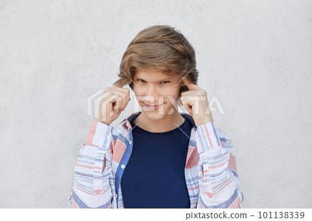 Portrait of handsome male with trendy hairstyle holding fingers on temples trying to concentrate and to get idea having serious and thoughtful look. Teenager remembering something important in life 101138339