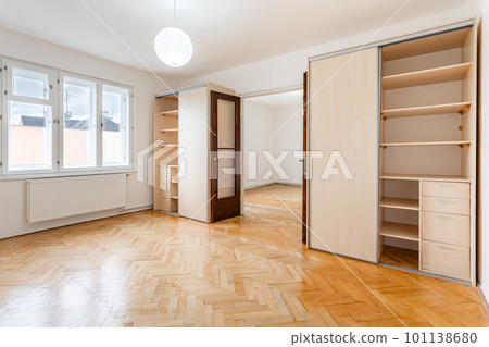 an empty room in an apartment with a wardrobe and a wooden parquet floor 101138680