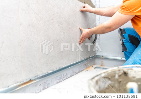 installation of large format tiles on the wall by a craftsman 101138681