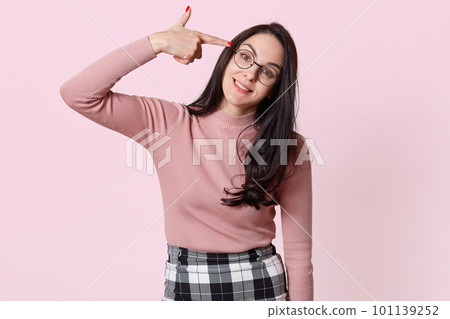 Image of young woman committing suicide with finger gun gesture, shooting herself making finger pistol sign, sick and tired of hearing her mother s teachings, wearing shirt, skirt and spectacles. 101139252