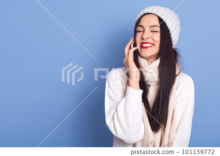 Cheerful pretty brunette girl talking on phone and laughing carefree, holding smartphone near ear, standing isolated over blue background, copy space for advertisement for promo. Cheerful pretty brunette girl talking on phone and laughing carefree, holding smartphone near ear, standing isolated over blue background, copy space for advertisement for promo. 101139772
