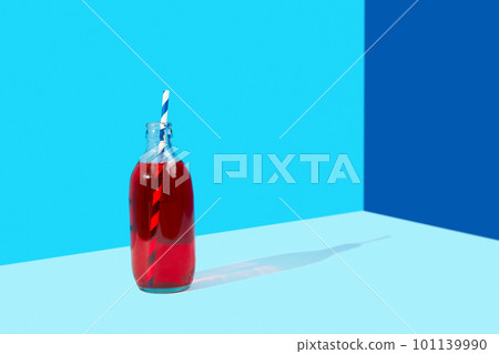 Refreshing cranberrie lemonade cocktail in bottle with palm leaf on blue creative background 101139990