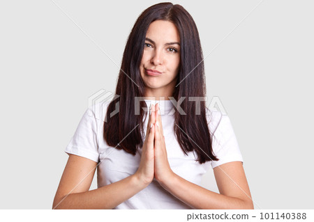 Dark haired model of european appearance about twenty five years, poses on isolated gray background in stylish white clothes that allows you to focus all your attention to face of amazing girl. 101140388