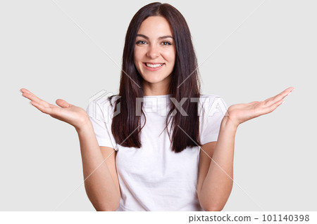Isolated shot of joyful brunette pretty woman laughing happily when she sees or hears something funny, has medium dark hair, poses on gray studio wall. Concept of happiness and positive emotions. Isolated shot of joyful brunette pretty woman laughing happily when she sees or hears something funny, has medium dark hair, poses on gray studio wall. Concept of happiness and positive emotions. 101140398