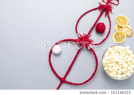 Flat lay Bulgarian Traditional Cornel Christmas Stick With Dried Fruits, Orange, Red, White Threads, Popcorn. Survakane, Survachka, Surva On Gray Background.Copy space For text,Horizontal Plane Flat lay Bulgarian Traditional Cornel Christmas Stick With Dried Fruits, Orange, Red, White Threads, Popcorn. Survakane, Survachka, Surva On Gray Background.Copy space For text,Horizontal Plane 101140555