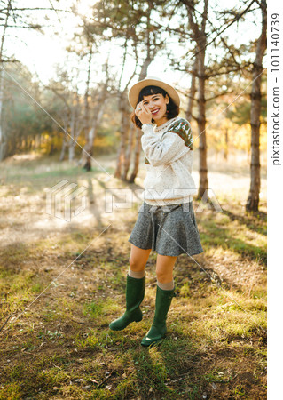 Lovely girl with a beautiful smile at sunset in the forest. The girl is dressed with a hat. Lovely girl with a beautiful smile at sunset in the forest. The girl is dressed with a hat. 101140739