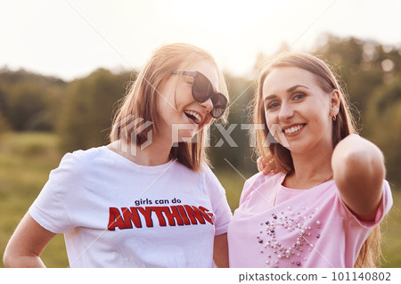 Joyful positive teenagers have fun together, charming smiles on faces, breath summer air and admire beautiful nature, come on picnic to spend weekends. People, leisure and recreation concept 101140802