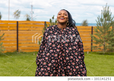Summer portrait of beautiful african american woman in colourful dress wear standing on backyard. Suburban lifestyle and chilling on weekend in countryside and inclusion with diversity concept 101141251