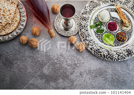 Passover Seder plate with traditional food, walnuts, matza and wine on grunge background 101141404