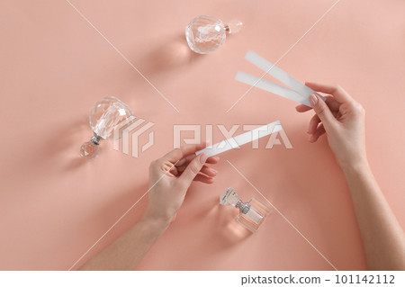 Woman with perfume testing stripes on peach background, top view 101142112