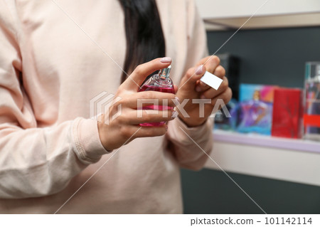 Young woman spraying perfume on blotter in shop, closeup Young woman spraying perfume on blotter in shop, closeup 101142114