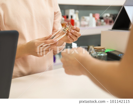 Young woman helping customer to choose perfume in shop, closeup Young woman helping customer to choose perfume in shop, closeup 101142115