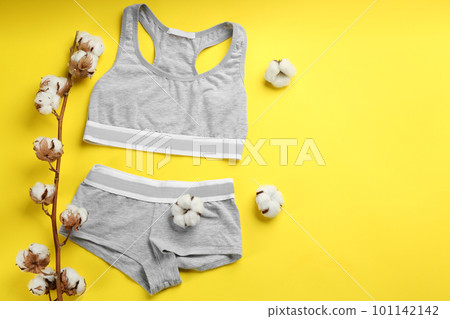 Sports women's underwear and cotton flowers on yellow background, flat lay. Space for text 101142142