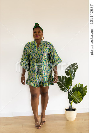 Portrait of cheerful african american woman with headscarf turban against white wall. Happy smiling lady wearing traditional african scarf 101142687