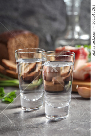 Cold Russian vodka with snacks on grey table, closeup 101143262