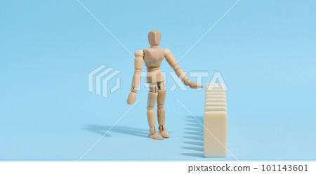 Wooden toy mannequin keeps dominoes from falling, risk prevention concept 101143601