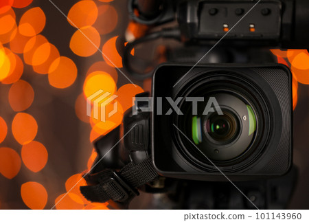 Modern video camera against blurred lights, closeup 101143960