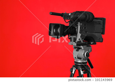 Modern professional video camera on red background Modern professional video camera on red background 101143969