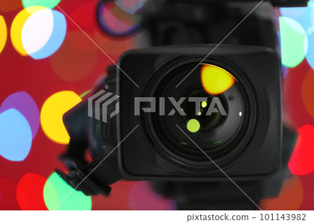 Modern video camera against blurred colorful lights, closeup 101143982