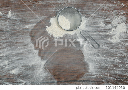 Flour and strainer on wooden table, top view. Space for text 101144030