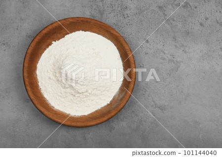 Wooden bowl with flour on light grey table, top view. Space for text 101144040