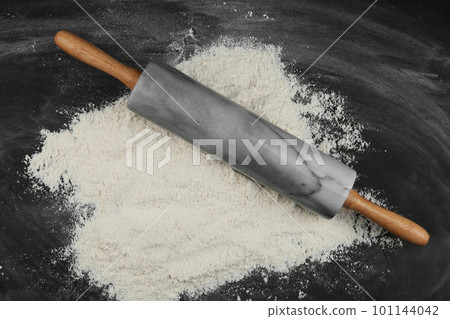 Flour and rolling pin on black table, top view Flour and rolling pin on black table, top view 101144042