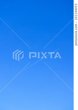 A contrail of a jet airliner cutting diagonally in the blue sky 101144053