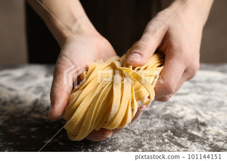 Woman holding pasta at table, closeup view Woman holding pasta at table, closeup view 101144151