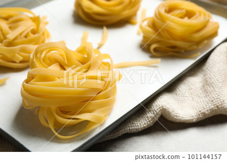 Raw tagliatelle pasta in baking pan, closeup view Raw tagliatelle pasta in baking pan, closeup view 101144157