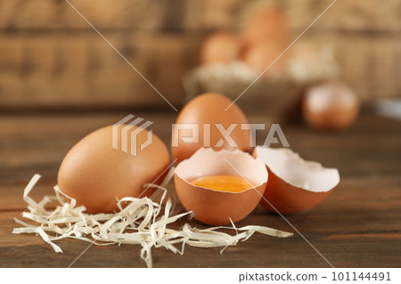 Raw brown chicken eggs and decorative straw on wooden table 101144491