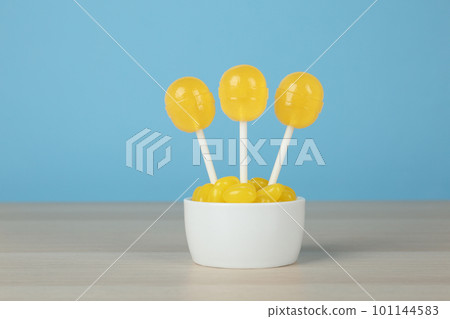 Delicious lemon drops and lollipops on wooden table against light blue background 101144583