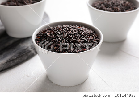 Uncooked brown rice in bowl on white table, closeup 101144953