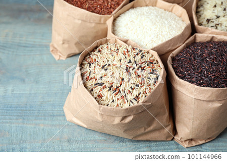 Brown and polished rice in paper bags on blue wooden table 101144966
