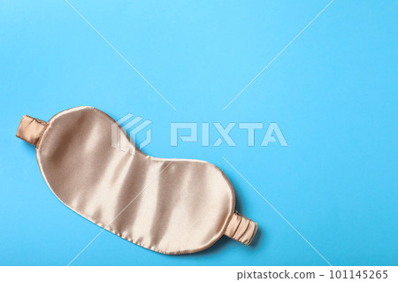 Beige sleeping mask on light blue background, top view with space for text. Bedtime accessory Beige sleeping mask on light blue background, top view with space for text. Bedtime accessory 101145265