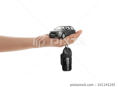 Woman holding key and miniature automobile model on white background, closeup. Car buying 101145285