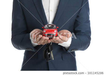 Man holding key and miniature automobile model on white background, closeup. Car buying 101145286