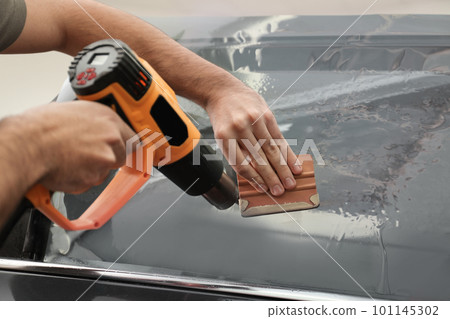 Worker tinting car window with heat gun in workshop, closeup 101145302