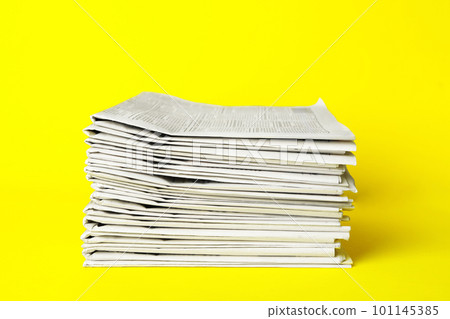 Stack of newspapers on yellow background. Journalist's work 101145385