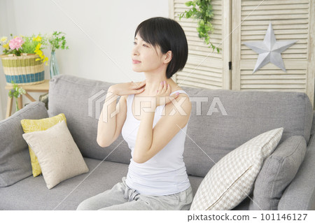 A woman doing a self-massage on her neck in the living room 101146127