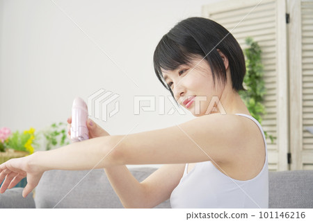 一位女士在客廳用家用脫毛器在手臂上進行自我脫毛 一位女士在客廳用家用脫毛器在手臂上進行自我脫毛 101146216