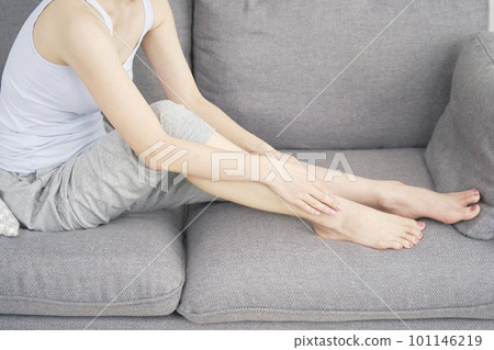 A woman self-depilating her legs with a household epilator in the living room Faceless A woman self-depilating her legs with a household epilator in the living room Faceless 101146219